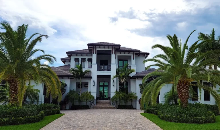 A clean, pressure-washed concrete driveway leading to a beautiful white house in Hollywood, Florida, showcasing enhanced curb appeal.