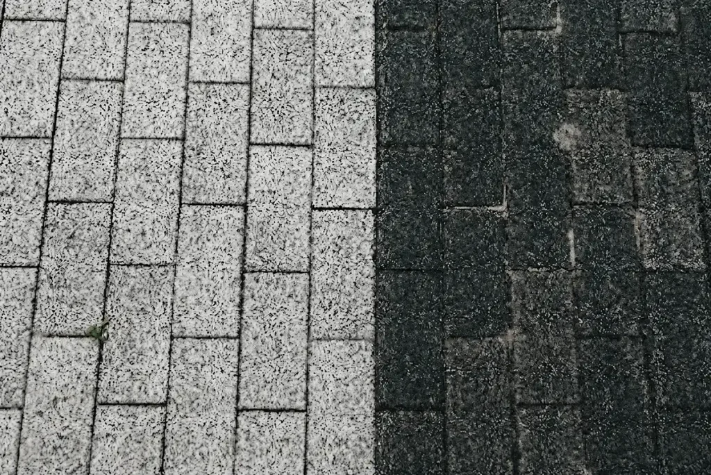 A stark before and after contrast split on brick pavers showing the deep cleaning results of a professional power washing service.