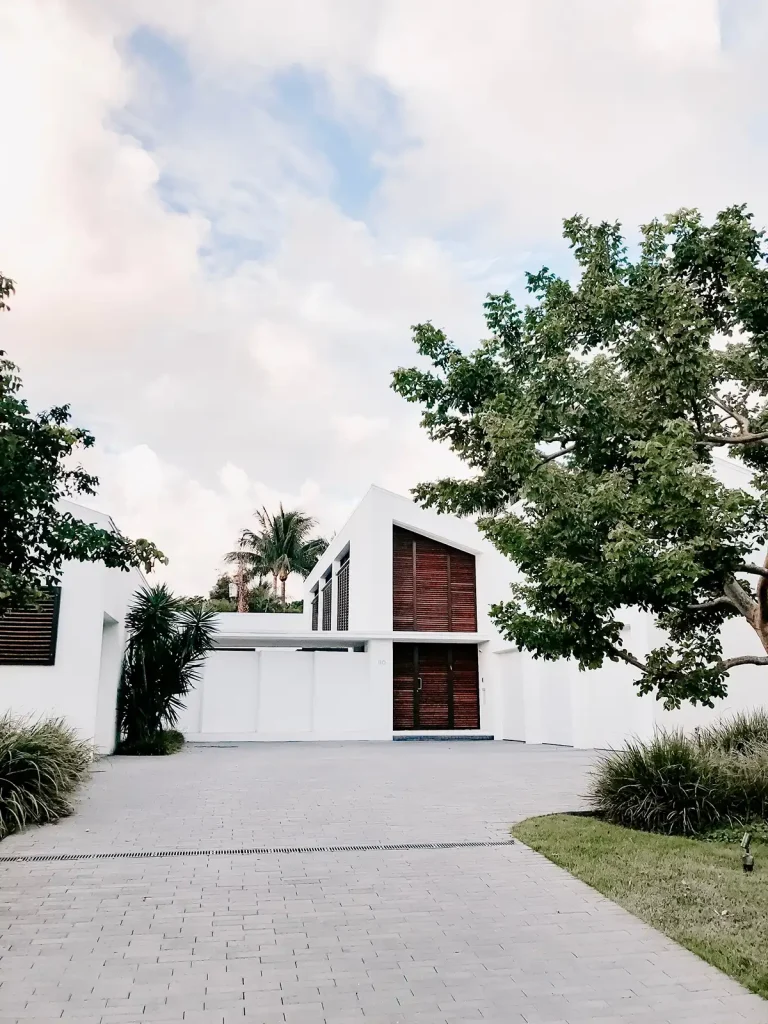 A clean, realistic, modern concrete paver driveway leading to a contemporary luxury white villa in South Florida.